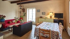 Ein gemütliches Wohnzimmer mit einer Couch, einem Esstisch mit Stühlen, einem Fernseher und einer Lampe.