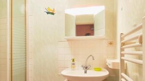 Ein Badezimmer mit einem weißen Waschbecken, einem Spiegel darüber und einem Handtuchhalter.