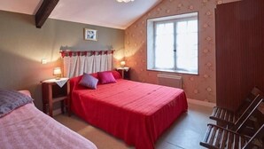 Ein Schlafzimmer mit einem großen Bett, einem Fenster, einem Heizkörper und einem Holzstuhl.