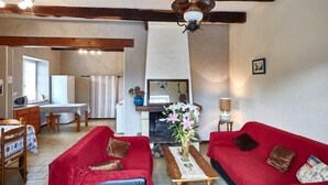 Ein gemütliches Wohnzimmer mit Kamin, roten Sofas, einem Holztisch und einem Fernseher.