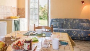 A dining area with a table set for two, a bowl of strawberries, a jar of jam, and a glass of water.
