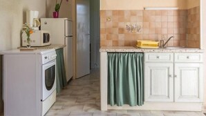 A compact kitchen with white cabinets, a microwave, a refrigerator, and a sink.