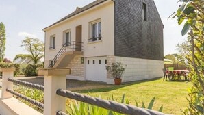 A two-story house with a balcony, a small garden, and a paved driveway. - Cozy Countryside Cottage near Brière Park with Garden, WiFi, and Modern Amenities (Missillac)