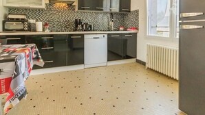 A compact kitchen with dark cabinets, a microwave, a coffee maker, and a dishwasher. - Cozy Countryside Cottage near Brière Park with Garden, WiFi, and Modern Amenities (Missillac)
