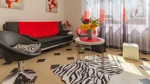 A modern living room with a black sofa, a zebra-patterned rug, and abstract art on the walls. - Cozy Countryside Cottage near Brière Park with Garden, WiFi, and Modern Amenities (Missillac)