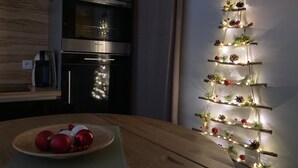 A kitchen with a wooden table, a plate of red ornaments, and a wall-mounted Christmas decoration. - Charming Renovated Cottage Near Beaches and Shops with Private Garden and Modern Amenities (Batz-sur-Mer)