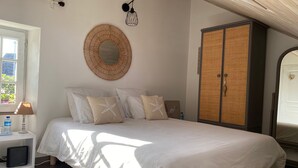 A bedroom with a bed, bedside table, lamp, and a wardrobe. - Charming Renovated Cottage Near Beaches and Shops with Private Garden and Modern Amenities (Batz-sur-Mer)