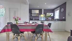 A modern kitchen with white cabinets, a grey countertop, and a dining area with a table set for four.