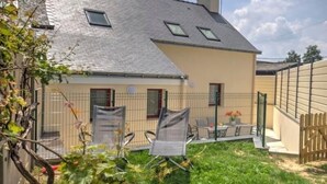 A house with a sloped roof, a fenced backyard, and a small patio with outdoor furniture.