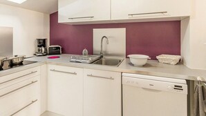 A compact kitchen with white cabinets, a sink, a coffee maker, and a dishwasher. - Quiet gîte, WiFi, near Pornic, 4 guests (Pornic-Le Clion sur Mer)