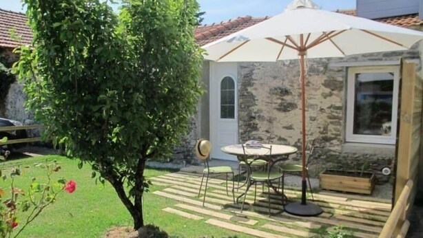 A patio area with a table and chairs, a small tree, and a wooden planter. - Quiet gîte, WiFi, near Pornic, 4 guests (Pornic-Le Clion sur Mer)