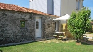 A stone building with a tiled roof, a door, and a small garden area with a table and chairs. - Quiet gîte, WiFi, near Pornic, 4 guests (Pornic-Le Clion sur Mer)