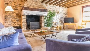 A cozy living room with a stone fireplace, comfortable seating, and a television.