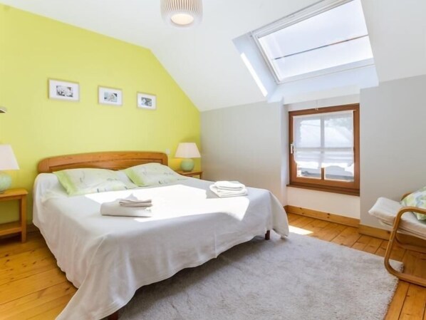 Une chambre à coucher avec un lit, deux tables de chevet, une fenêtre et un puits de lumière.