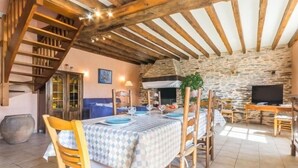 A rustic dining area with a stone wall, wooden beams, and a checkered tablecloth.