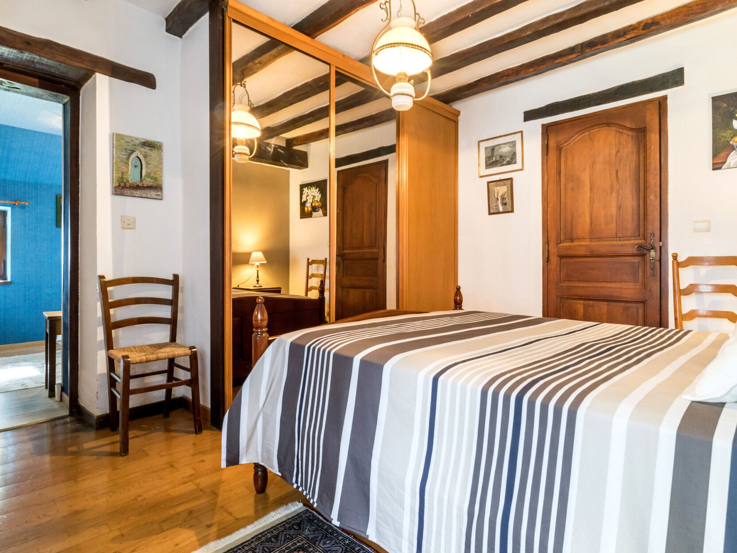 Une chambre à coucher avec un lit, une armoire en bois et une chaise.