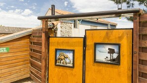 A wooden gate with two framed pictures, one of a dinosaur and one of a boat, and a sign that reads "GITE NATUREL".