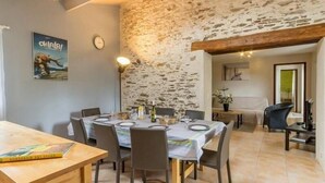 A dining area with a stone wall, wooden ceiling beams, and a table set for four.