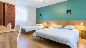 A hotel room with two single beds, a wooden desk, and a window with curtains.