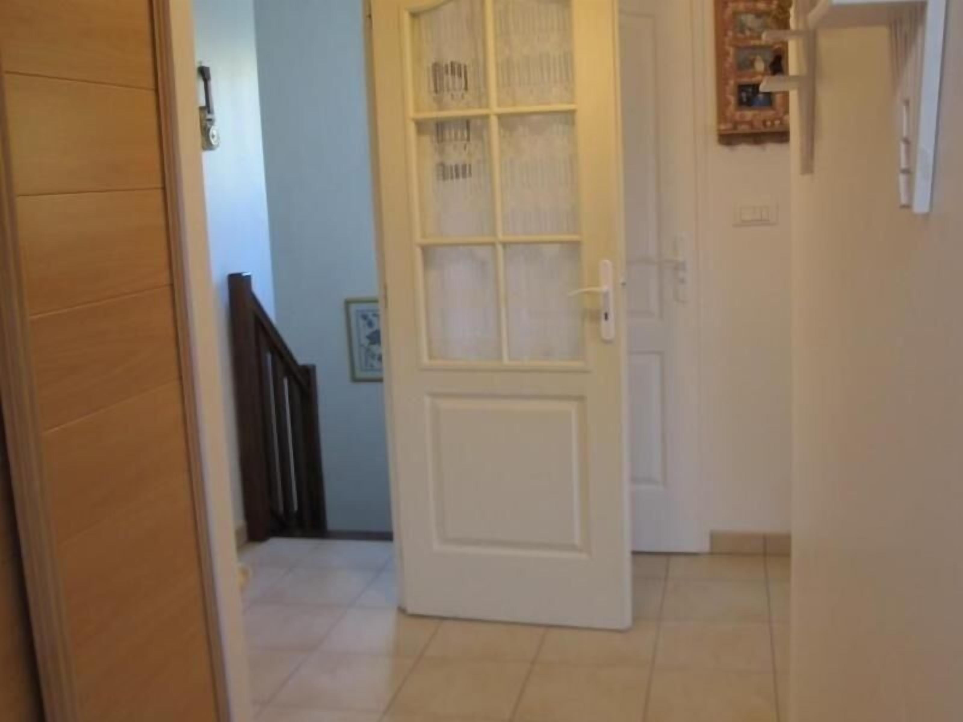 A hallway with a white door, a staircase, and a tiled floor.
