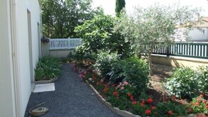 Ein Garten mit Kiesweg, verschiedenen Pflanzen und einem weißen Zaun.