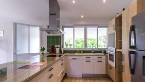 Une cuisine moderne avec des meubles en bois, un réfrigérateur en acier inoxydable et une fenêtre qui laisse entrer la lumière naturelle.