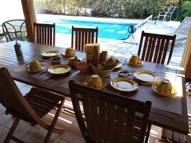 Uma mesa de jantar posta para refeição, com pratos, xícaras amarelas e uma cesta de pão.