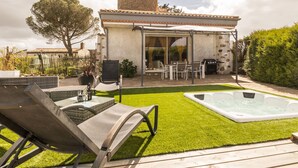 A patio with a hot tub, outdoor seating, and a stone tower.