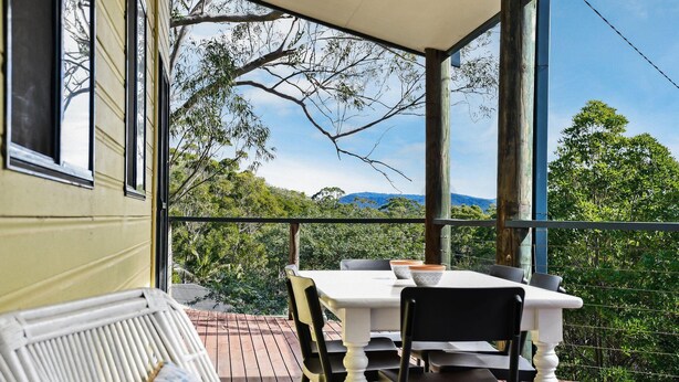 A balcony with a table and chairs, overlooking a lush landscape with trees and mountains. - Paws and Relax - accommodates the whole family including your fur babies (Elizabeth Beach)