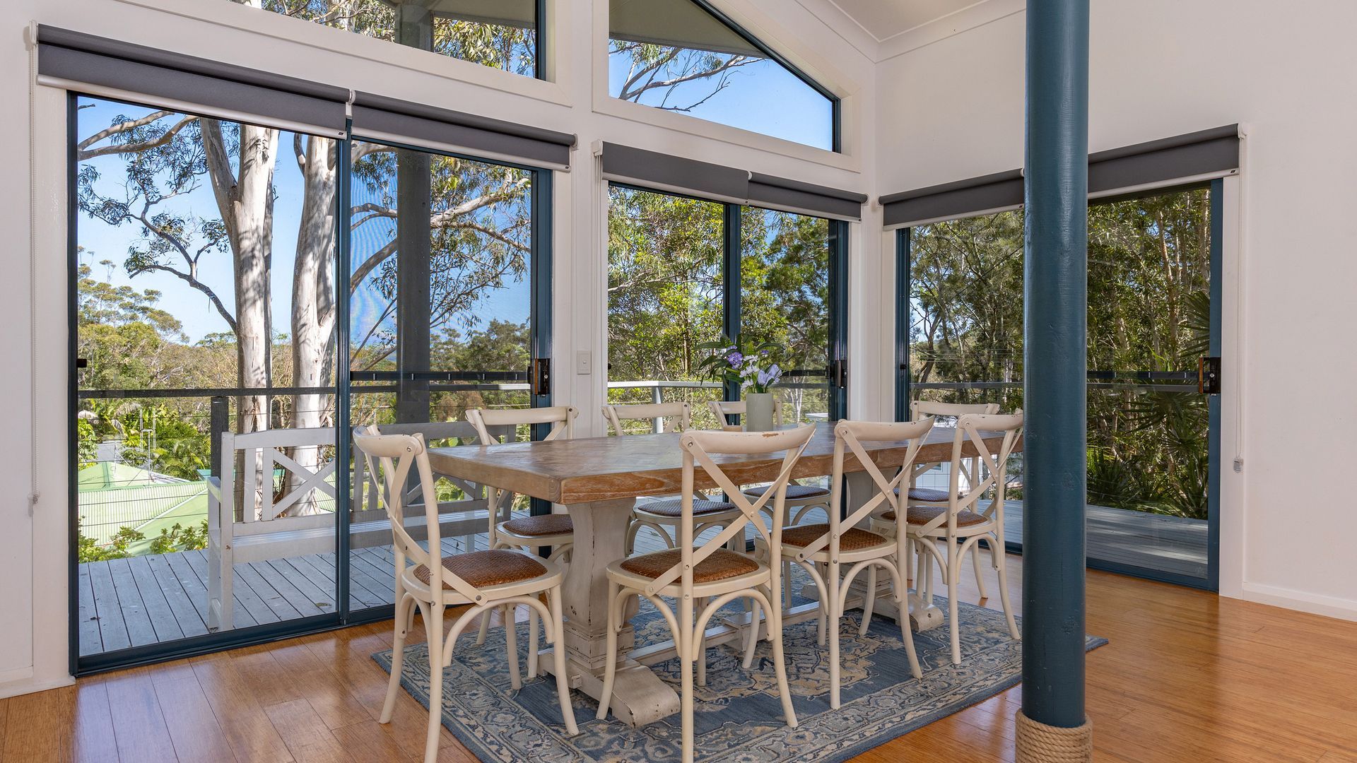 A spacious room with a large table and chairs, large windows, and a view of trees.
