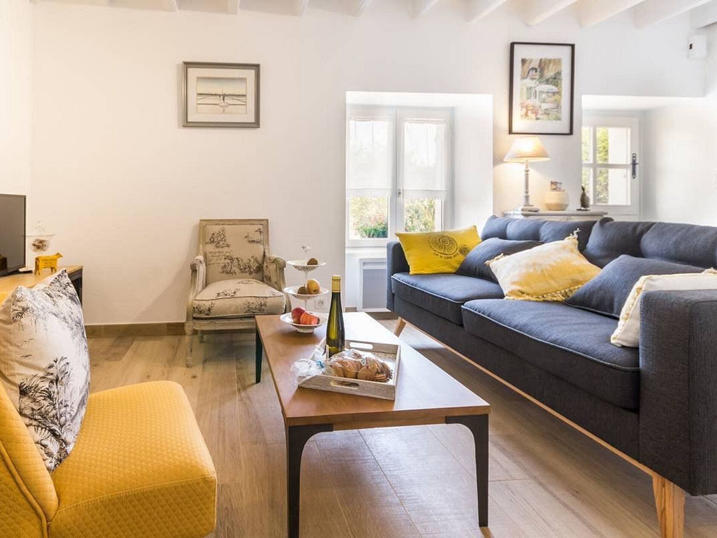 Een woonkamer met een bank, fauteuil en een kleine tafel met eten en drinken.