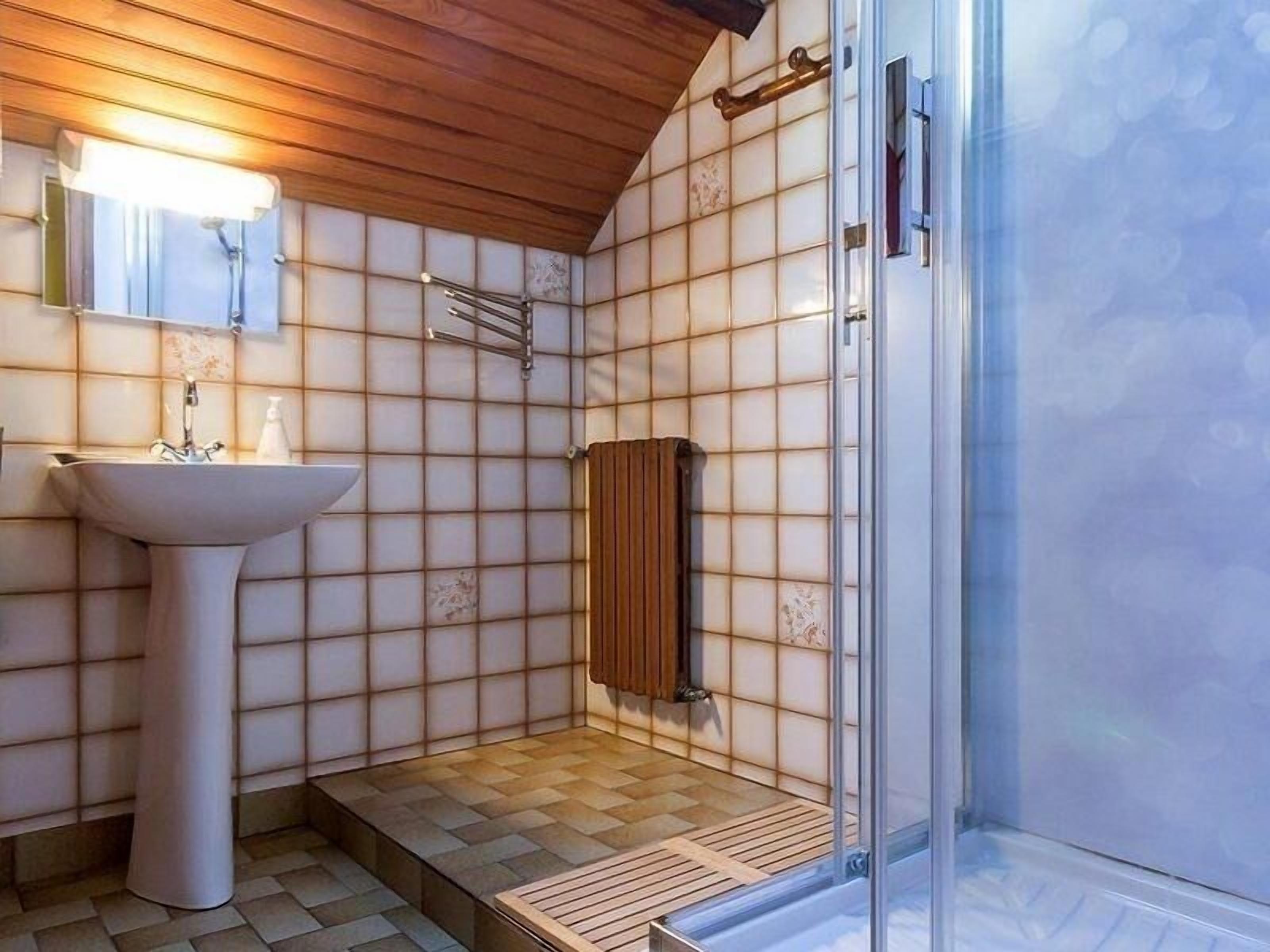 A bathroom with a sink, mirror, and shower.