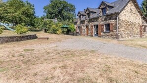 A stone house with a gravel driveway and a small patio area. - Stone House Retreat with Garden & WiFi in Tranquil Countryside (Moisdon-la-Rivière)