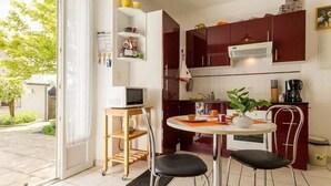 Cuina compacta amb zona de dinar, microones, cafetera i una planta en test.