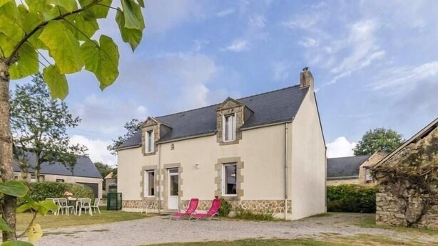 Une maison à deux étages, avec des fondations en pierre, un toit à deux versants et une allée gravillonnée.