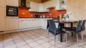 Une cuisine moderne avec des meubles blancs, une cuisinière noire et un sol carrelé.