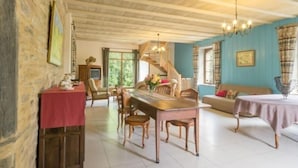 Una habitación amplia con una mesa de madera para comer, sillas, un sofá y una escalera que sube a un nivel superior.