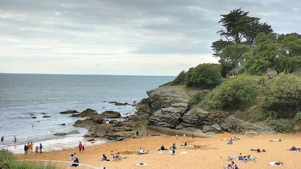 A beach with rocky outcrops, people sunbathing, and a tree on the right. - Seaside Eco Cottage: 18th-Century Stone House near Pornic, 15min to Beach, Accessible, Private Garden (Arthon-en-Retz)