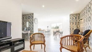 Un salon moderne doté d’un téléviseur à écran plat, de meubles en bois et d’un papier peint à motifs.