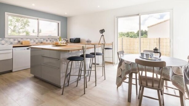 Une cuisine moderne dotée d’un îlot central, de tabourets de bar et d’une table à manger avec des chaises.