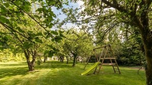 Un parc avec une balançoire en bois et un toboggan.