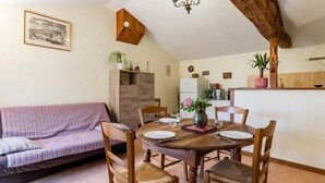 A cozy dining area with a wooden table, chairs, and a chandelier. - Charming Renovated Farmhouse with Pond, Near Nantes - WiFi, Baby Equipment Included (Corcoué-sur-Logne)