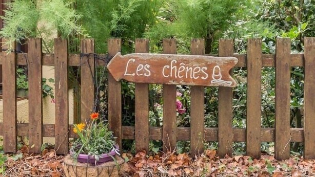 A wooden sign with the text "Les chênes" in a garden setting. - Charming Renovated Farmhouse with Pond, Near Nantes - WiFi, Baby Equipment Included (Corcoué-sur-Logne)