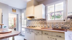 Une cuisine moderne avec des meubles blancs, un crédence à motifs et une fenêtre décorée de fleurs.