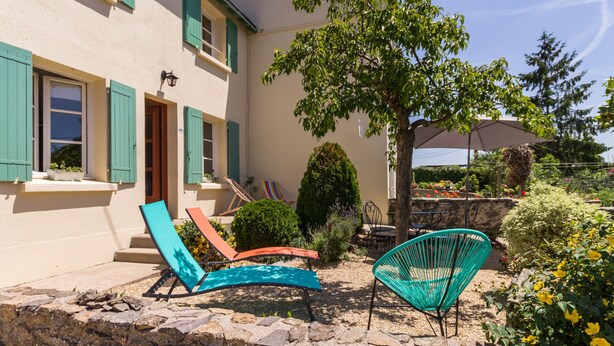 Un bâtiment à la façade en pierre, avec un arbre et des sièges à l’extérieur.