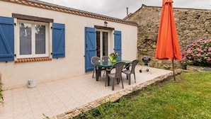 A house with a patio, a table with chairs, and a barbecue grill.