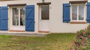 A building with three windows, each with blue shutters, and a small porch area.