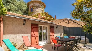 Un patio con mobiliario exterior, una mesa de comedor y una zona cubierta.