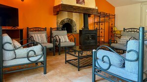 A cozy living room with a stone fireplace, two sofas, and a TV. - Countryside Retreat: Cozy 3-Bed Gîte with Garden, Terrace & Petanque near Pornic (Frossay)