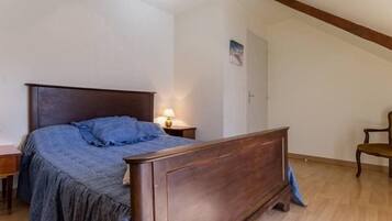 Ein Schlafzimmer mit einem hölzernen Bett, einem Nachttisch, einer Lampe und einem Sessel.